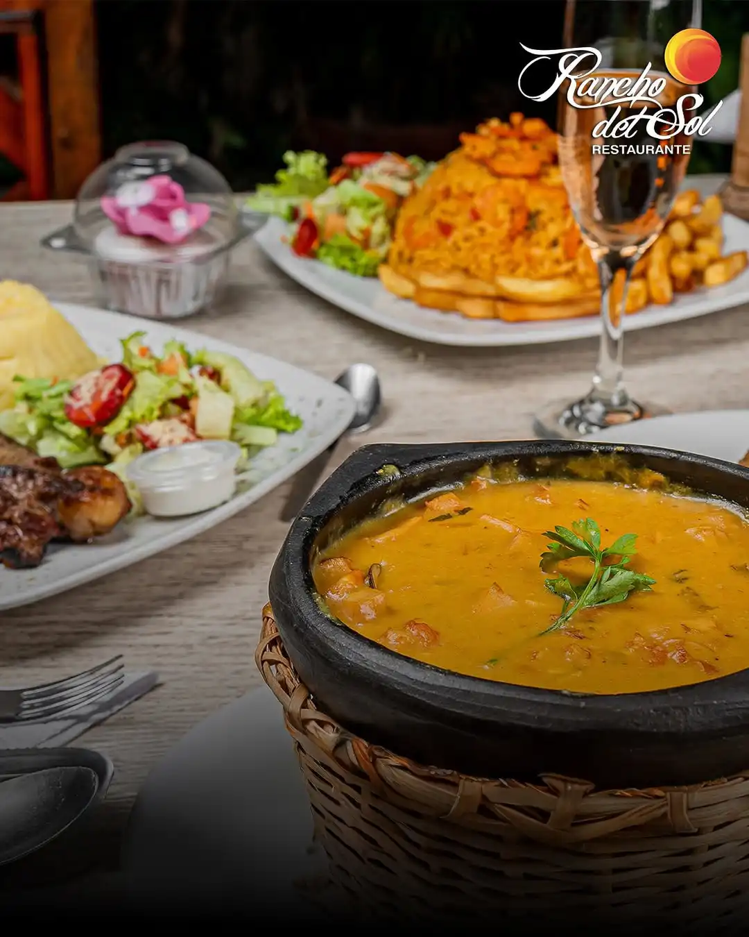 Cazuela de mariscos servida en recipiente de barro, acompañada de platos típicos de La Guajira en mesa de restaurante.