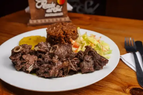 Plato de Friche, acompañado de arroz de coco, patacones y ensalada fresca, servido en el restaurante Rancho del Sol, especialista en comida de La Guajira, Colombia.